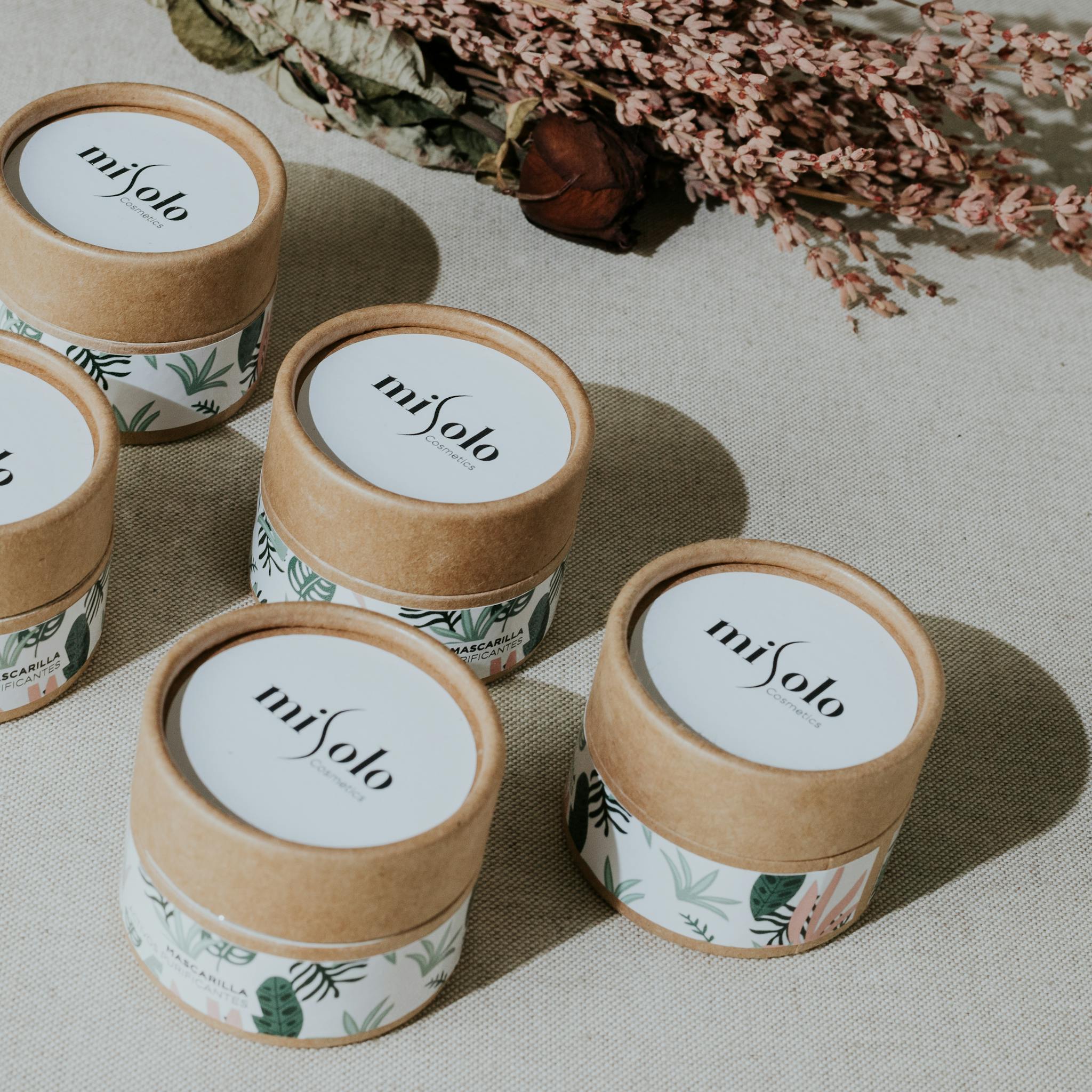 Flat lay of stylish botanical skincare containers with floral accents.