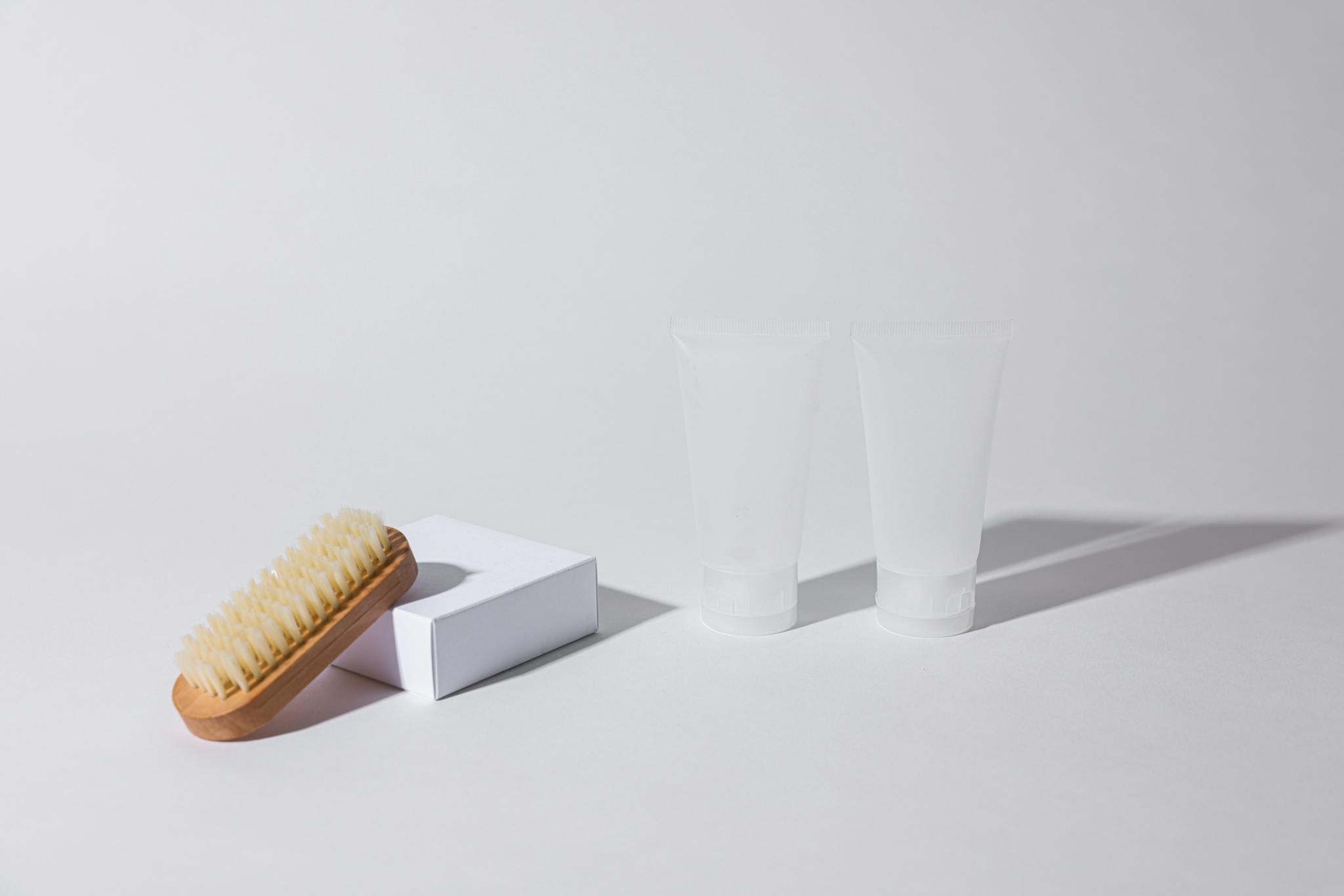 Simple arrangement of a brush and tubes on a white background with shadows.
